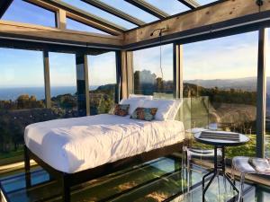 a bedroom with a bed in a room with large windows at Atatū PurePod in Tormore