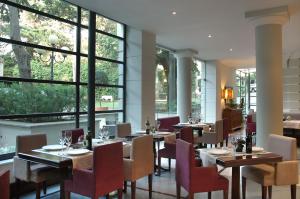 a restaurant with tables and chairs and large windows at Hotel Flora in Frascati