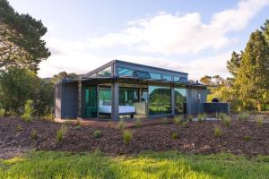a glass house in the middle of a field at Matū PurePod - Waitomo in Otorohanga