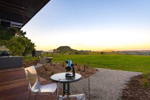a table and chairs on a patio with a view at Matū PurePod - Waitomo in Otorohanga