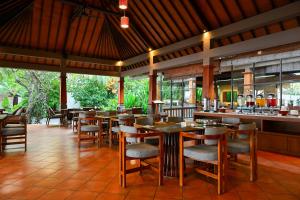 ein Restaurant mit Tischen und Stühlen und einer Bar in der Unterkunft The Grand Villandra Resort Lovina in Lovina