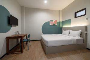 a bedroom with a bed and a table and a desk at Cove Haven in Surabaya