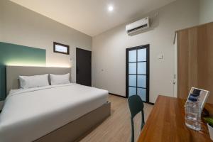 a bedroom with a white bed and a desk and a table at Cove Haven in Surabaya