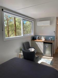 a bedroom with a bed and two chairs and a window at The Barn Top Noojee in Noojee