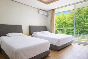 two beds in a room with a large window at Gyeongju Ilsung Condo in Gyeongju