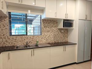 a kitchen with white cabinets and a sink and a window at 3 bedroom fully air conditioned family home -spacious, free parking in Suva