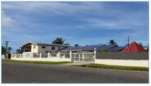 a white fence in front of a house with a red roof at 3 bedroom fully air conditioned family home -spacious, free parking in Suva