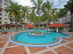 a pool at a resort with palm trees and buildings at Marbella Place Anyer by Jayakarta in Kamasan