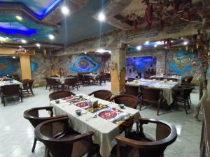 a dining room with tables and chairs and paintings on the walls at Golubie Kupola Hotel 华人酒店 in Bukhara