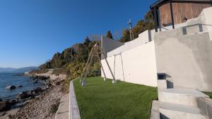 a building with a grassy yard next to the water at Namioto Villa YOSA in Hama +33 photos