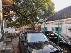 two cars parked in a parking lot next to a house at Ndalem Wongso in Yogyakarta