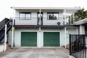 a white house with green garage doors and a balcony at Pembroke View in Carterton
