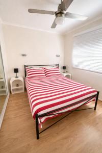 a bedroom with a bed with a red and white striped blanket at Badgee Park in Sussex Inlet