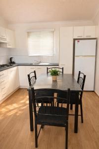 a kitchen with a black table and chairs in a room at Badgee Park in Sussex Inlet