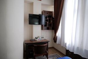 a room with a desk with a tv and a window at Golubie Kupola Hotel 华人酒店 in Bukhara