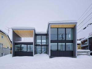 a house with glass doors in the snow at TsuTsu Furano by H2 Life in Furano