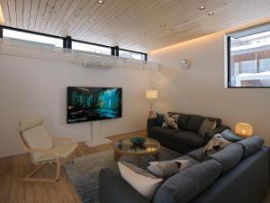 a living room with a couch and a tv on a wall at TsuTsu Furano by H2 Life in Furano