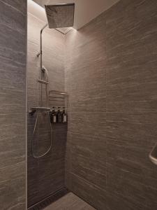 a bathroom with a shower with brown tiles at TsuTsu Furano by H2 Life in Furano +12 photos