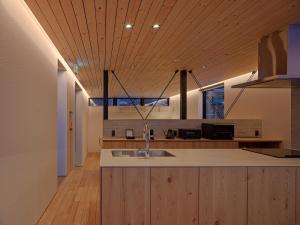 a kitchen with a sink and wooden ceiling at TsuTsu Furano by H2 Life in Furano