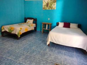 two beds in a room with blue walls and tile floors at koten Naj Cabanas in Xpujil