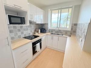 a kitchen with white cabinets and a sink and a microwave at Melrose Place at Flynn's Beach in Port Macquarie