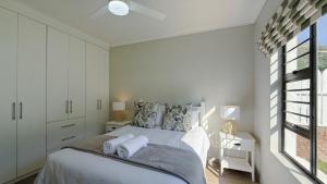 a white bedroom with a bed and a window at The Dock in Clarens