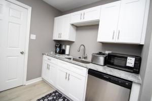 a kitchen with white cabinets and a sink and a microwave at Home Sweet Home Bungalow in North Little Rock