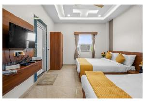 a hotel room with two beds and a flat screen tv at RS Resort in Ayodhya