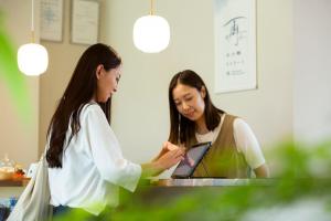 two women are looking at a tablet computer at 水の郷リトリート 再 in Katori