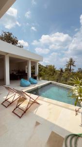 a swimming pool with two chairs and a house at Tris Villas ocean view in Kuta Lombok