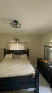 a bedroom with a bed and a dresser and a television at Stays at Global Dreams in Beckford Town