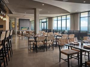 a dining room with tables and chairs and windows at Alila Marea Beach Resort Encinitas, a Hyatt Resort in Encinitas