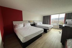 a hotel room with two beds and a window at Ramada by Wyndham Cobleskill in Cobleskill