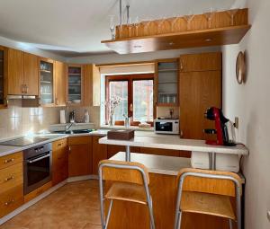 a kitchen with wooden cabinets and a counter with stools at Dům pod horami - Beskydy in Frýdlant nad Ostravicí