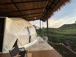 a porch with a swing and chairs on a deck at Mondara Villa and Glamping in Ban Bo Wi
