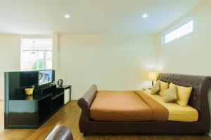 a bedroom with a bed with a couch and a television at Mondara Villa and Glamping in Ban Bo Wi