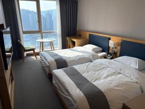 a hotel room with two beds and a window at 센텀스위트호텔 in Busan