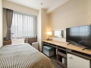a hotel room with a bed and a flat screen tv at Onomichi Daiichi Hotel in Onomichi