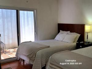 a bedroom with two beds and a large window at Hotel suites Las Abuelas in Copán Ruinas