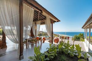 a patio with a table and chairs and the ocean at Dolce Vita Villa in Sampalan
