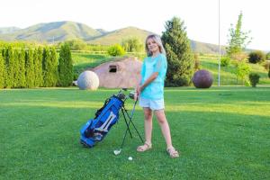 a girl is standing next to a golf bag at Arman Dala Resort in Qaskeleng