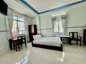 a bedroom with a bed and a table and two windows at NGỌC QUÝ Mini House in Quy Nhon