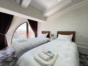 two beds in a room with a window at White House Apartment in Samarkand