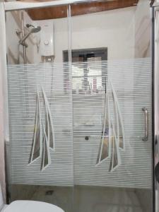 a glass shower door in a bathroom with a toilet at Guarin House in Sipating