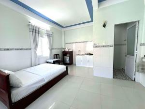 a white bedroom with a bed and a bathroom at NGỌC QUÝ Mini House in Quy Nhon