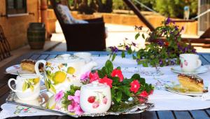 a table with tea cups and flowers on it at Il Giardino di Athena vista Valle dei Templi in Villaggio Peruzzo