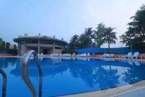 a large swimming pool with chairs and a building at Love Couple in Dhaka