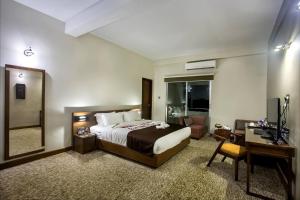 a bedroom with a bed and a desk and a mirror at Love Couple in Dhaka