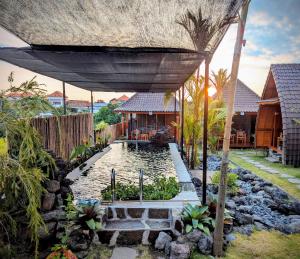 a large umbrella over a pond in a yard at Pondok Kayu Canggu in Dalung