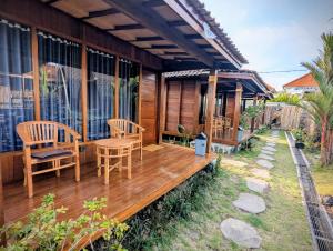 a wooden deck with chairs and a table at Pondok Kayu Canggu in Dalung